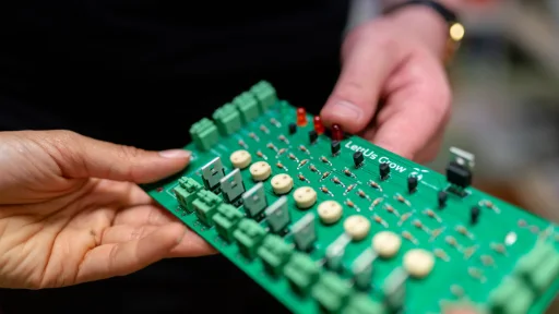 Hands holding an electronic circuit board for inspection
