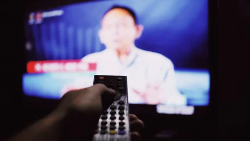 A person using a remote control in front of a television